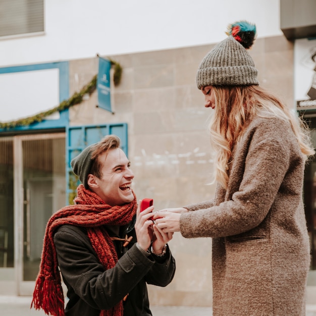 Foto gratuita uomo inginocchiato proponendo alla donna in strada