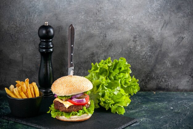 격리 된 회색 표면에 검은 쟁반에 맛있는 고기 샌드위치와 녹색 감자 튀김 고추 칼