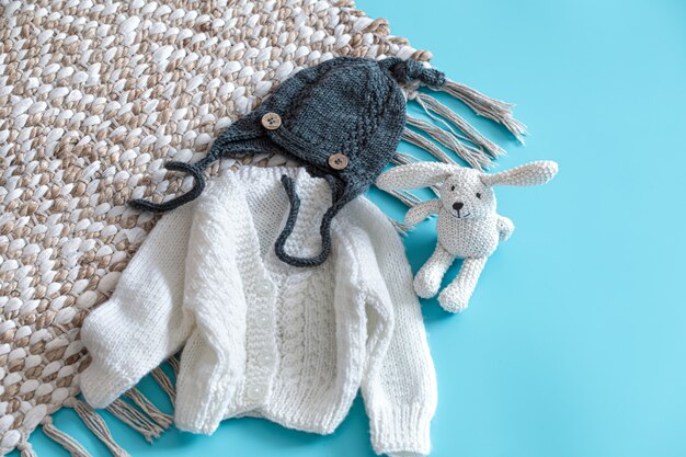 Knitted baby clothes and accessories on blue