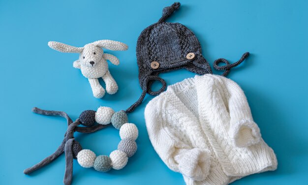 Knitted baby clothes and accessories on blue