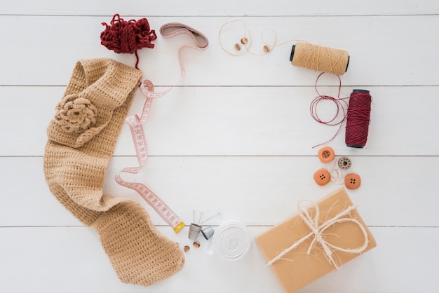 Knitted hosiery; wool; measuring tape; spool; button; wrapped gift box on wooden desk