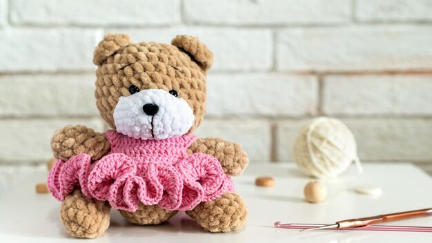 Knitted teddy bear with knitting equipment on the table