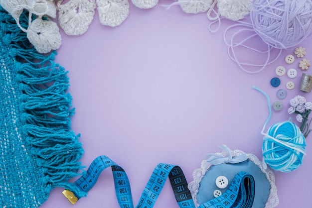 Knitted textile; wool ball; button; measuring tape on purple background with copy space for writing the text