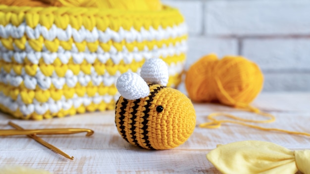 Knitted yellow bee toy with knitting equipment on the table