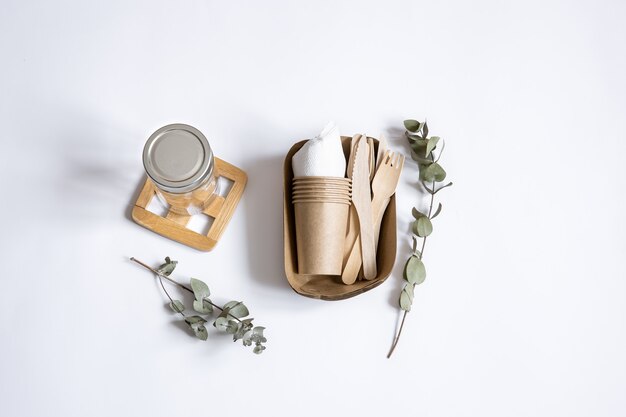 Knives, forks, dishes, glass jar, paper containers for food and a sprigs of eucalyptus. The concept of zero waste and plastic free.