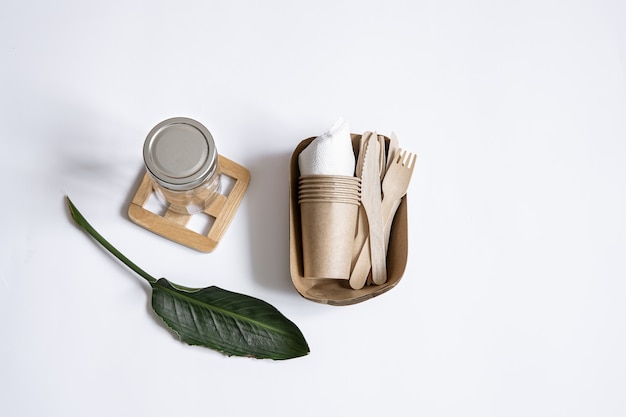 Бесплатное фото Ножи, вилки, посуда, стеклянная банка, бумажная тара для еды и натуральные листья. концепция без отходов и без пластика.
