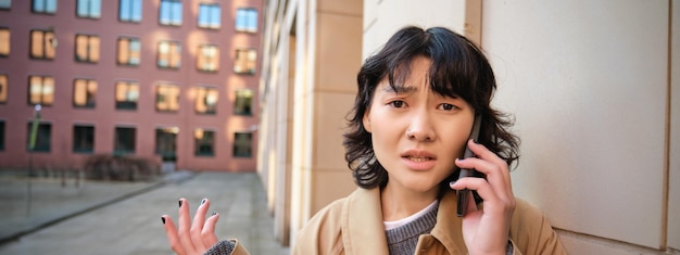 心配そうな顔をした韓国人の女の子が携帯電話で話し、顔をしかめて心配そうにしている