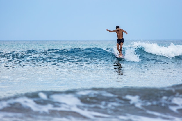 Korean surfer rides a longboard on blue waves