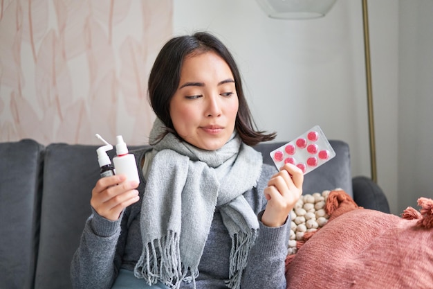 Korean woman showing medical pills sore throat sprays feeling sick staying at home as feeling unwell