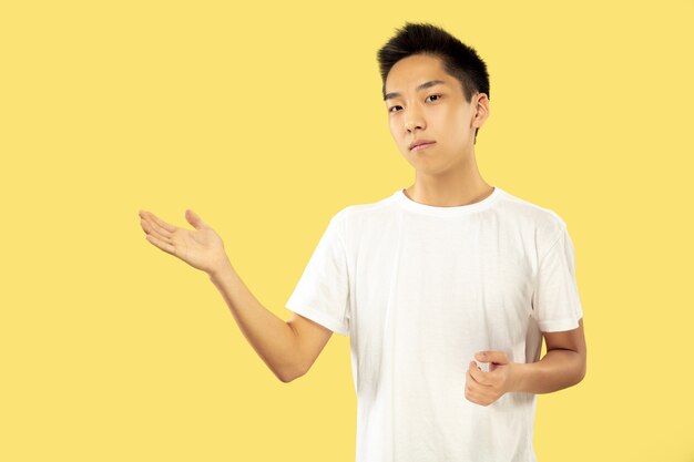 Портрет корейского молодого человека. Мужская модель в белой рубашке. Показывает что-то. Понятие о человеческих эмоциях, выражении лица. Передний план. Модные цвета.