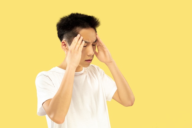 Korean young man's portrait. Male model in white shirt. Thinking serious. Concept of human emotions, facial expression. Front view. Trendy colors.