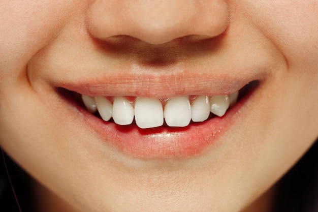 Korean young woman's close up portrait. Female model's smiling lips. Concept of human emotions, facial expression, beauty, self-care, cosmetics, spa. Front view.