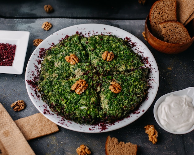 Kuku greenies pasto colorato con noce progettato all'interno del piatto bianco con pagnotte di pane yogurt su grigio