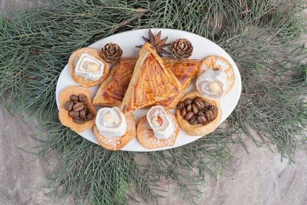 Kyatas, cookies, lokums and pine cones on a platter on marble. 