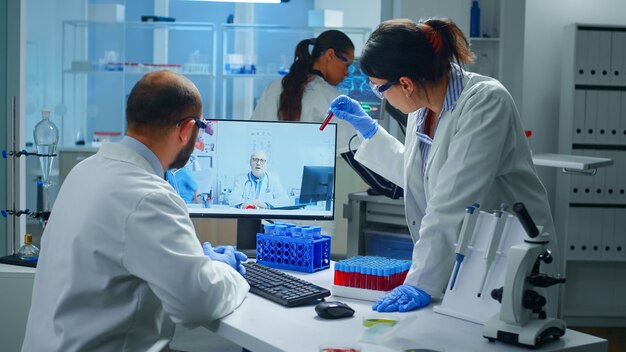 Lab technicians talking on video call with professional chemist doctor explaning vaccine reactions