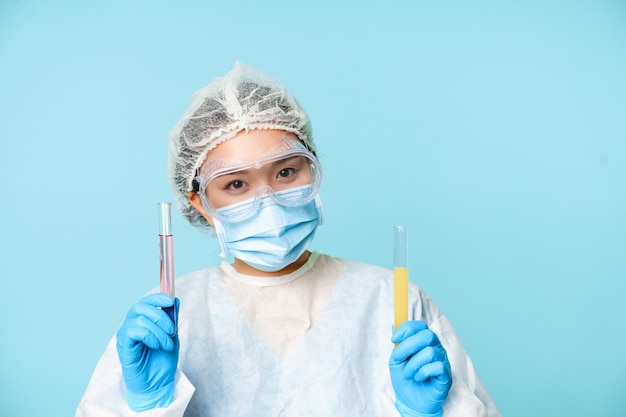 Концепция лабораторных и медицинских тестов, улыбающаяся азиатская женщина-врач, лабораторный работник, показывающий трубки с клини ...