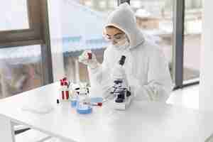 Free photo laboratory worker in coverall suit is adjusting microscope