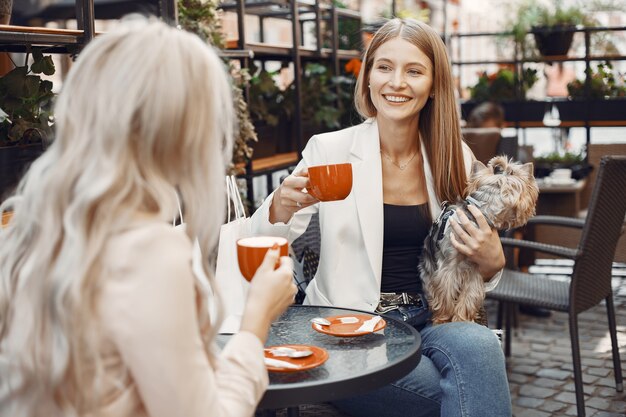 女性はコーヒーを飲みます。テーブルに座っている女性。かわいい犬と友達。