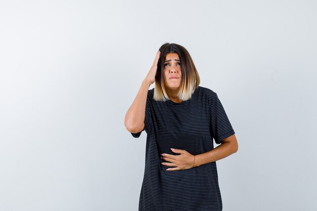 Lady in black t-shirt keeping hand on head and looking anxious , front view.