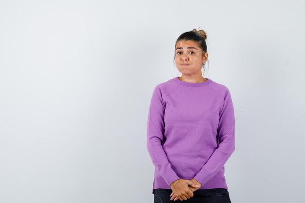 Lady blowing cheeks while looking at camera in wool blouse and looking confused