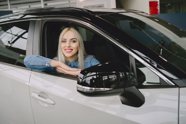 Lady in a car salon. Woman buying the car. Elegant woman in a blue dress.