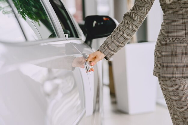 Lady in a car salon. Woman buying the car. Elegant woman in a brown suit.