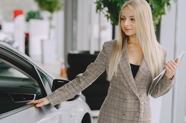 Free photo lady in a car salon. woman buying the car. elegant woman in a brown suit.