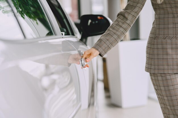 カーサロンの女性。車を買う女性。茶色のスーツを着たエレガントな女性。