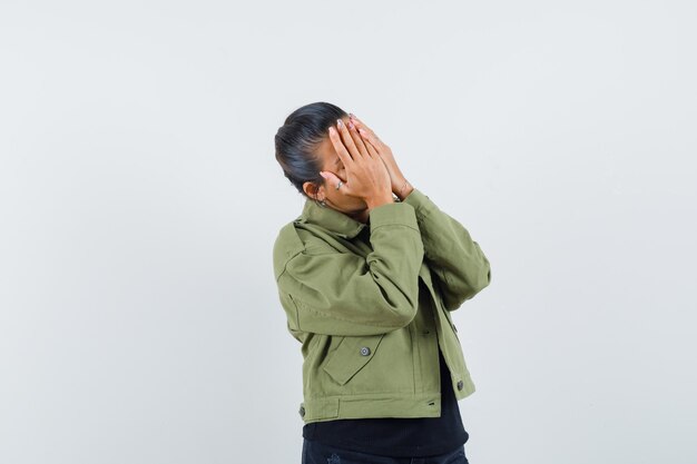 恥ずかしがりながら手の下に目を隠すお団子と赤毛の女の子 手で顔を覆っている因果服で深刻な若い女性 人間の顔の表情と感情 無料の写真