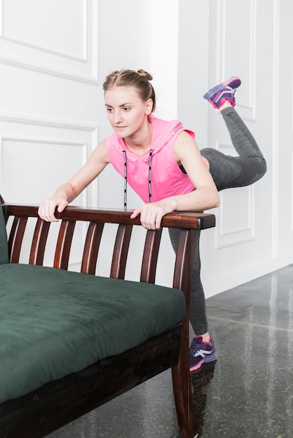 Lady doing legs lifting leaning on sofa