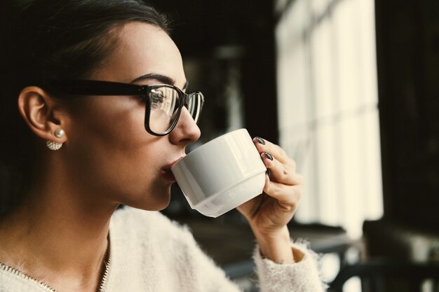 レディーはカフェでコーヒーを飲みながら彼女の時間を楽しんでいます