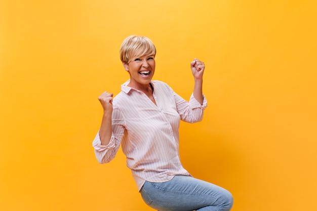 Lady in good mood rejoices on orange background