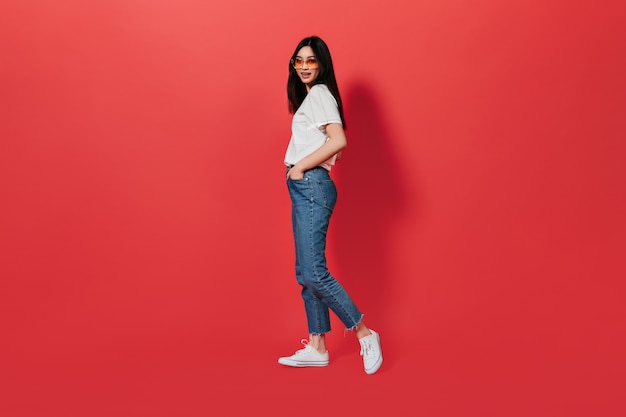 Lady in great mood is posing on red wall