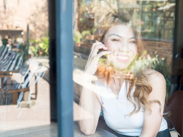 Lady happily using mobile phone in coffee shop