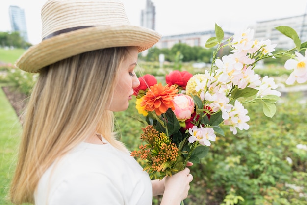 Signora con cappello con bouquet di fiori nel parco della città