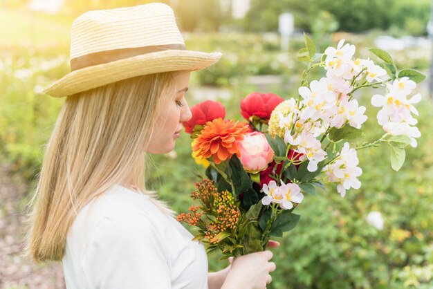 公園の花の花束と帽子の女性