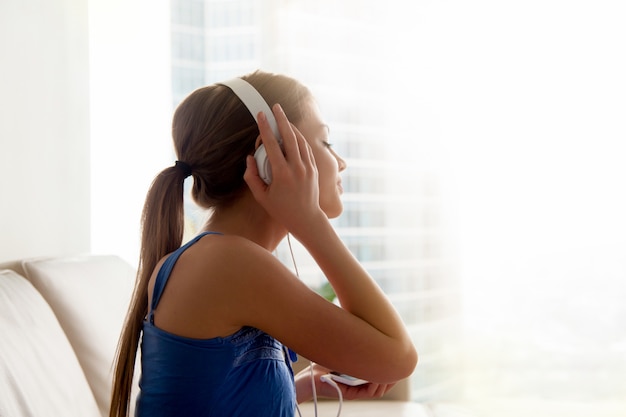 Lady in headphones listening classic music at home