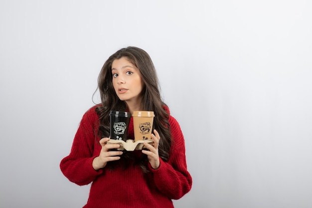 Lady hold coffee cups on carton holder .