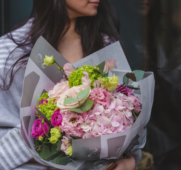 A lady holding a bouquet of seasonal flowers and sitting in the room 