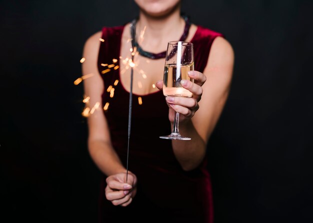 Lady holding burning Bengal lights and glass of drink