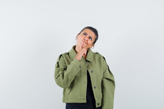 Lady holding finger on chin in jacket