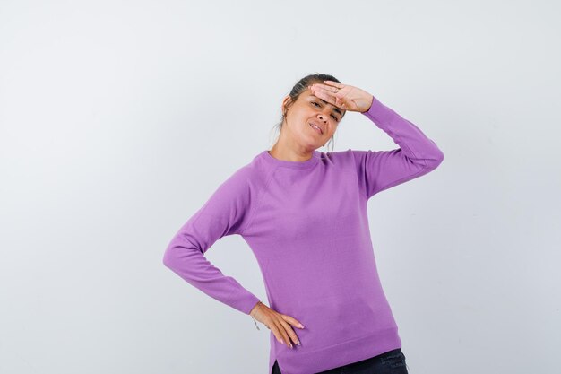 Lady holding hand on forehead in wool blouse and looking cute