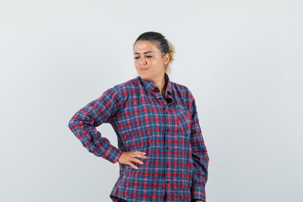 Lady holding hand on waist while posing in casual shirt and looking charming , front view.