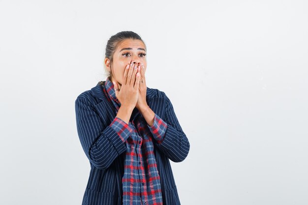 Lady holding hands on mouth in shirt, jacket and looking surprised , front view.