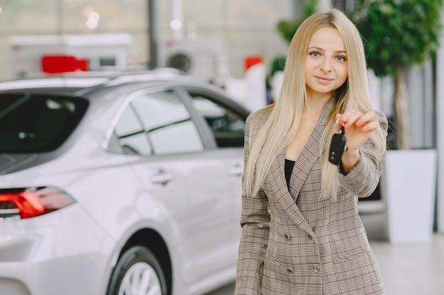 カーサロンの女性 車を買う女性 茶色のスーツを着たエレガントな女性 無料の写真