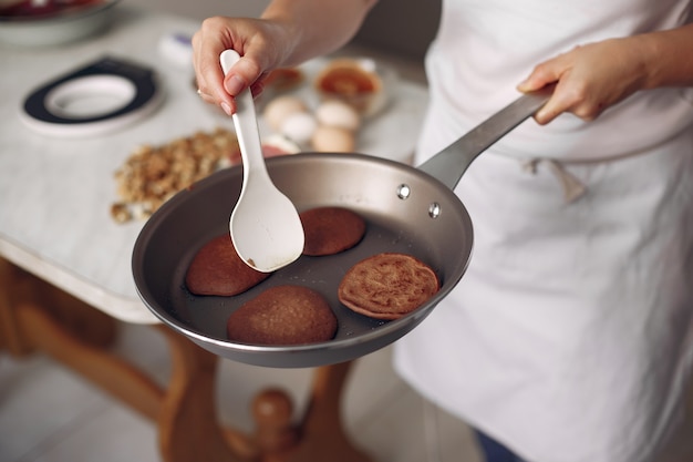 Lady is preparing dessert. Confectioner bakes a pancakes. Woman holds a frying pan in his hands.