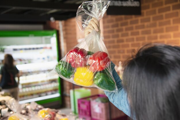 女性はスーパーマーケットで新鮮な野菜を買い物