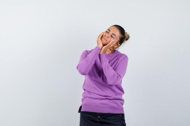 Lady keeping hands on cheeks in wool blouse and looking cute 