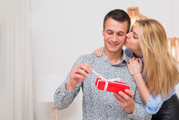 Lady kissing and embracing young guy with present