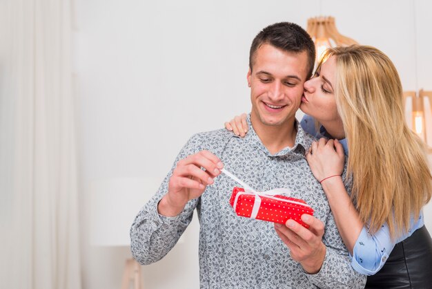 Lady kissing and embracing young guy with present